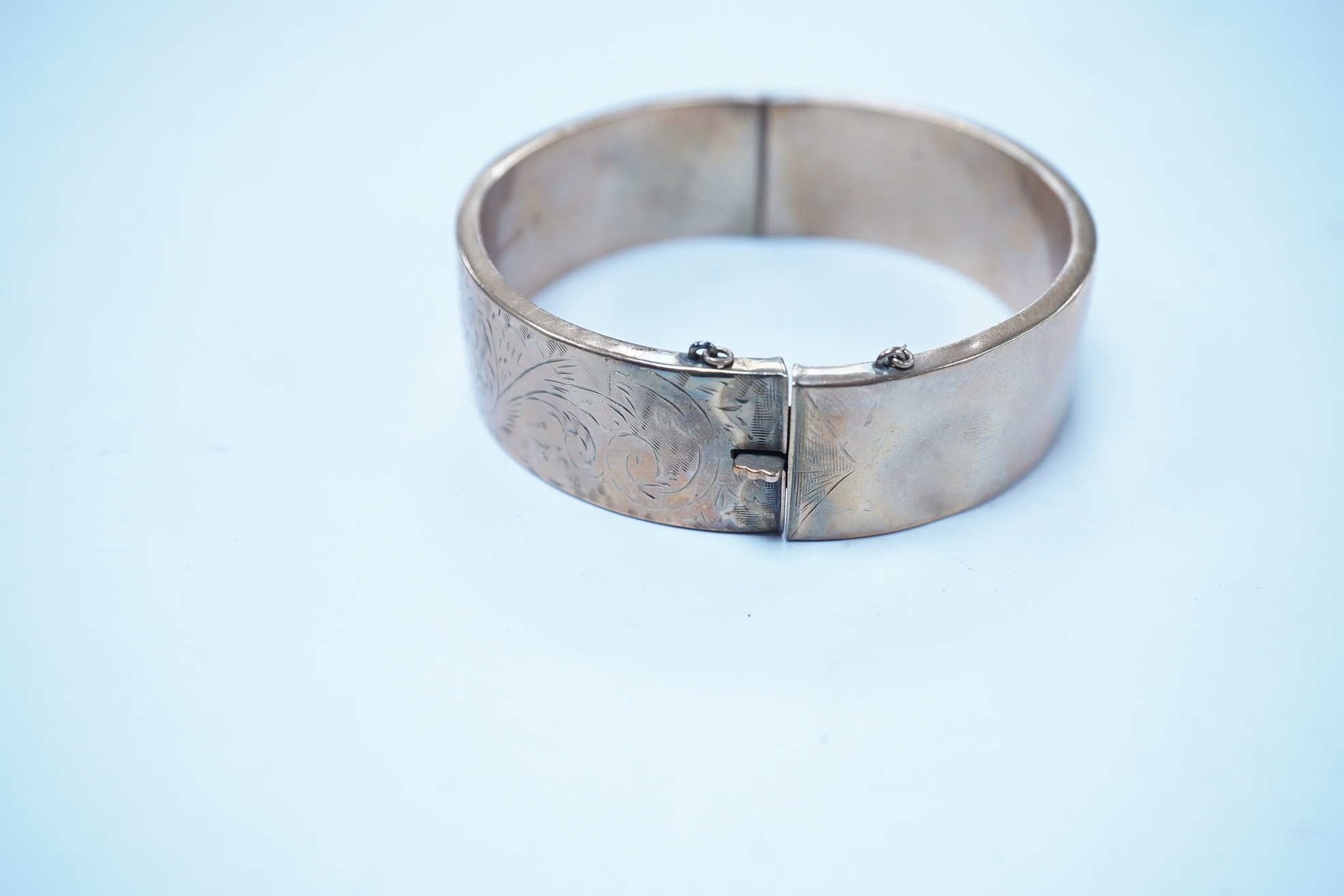 A 1960's engraved 9ct gold hinged bangle, 24.1 grams. Condition - poor